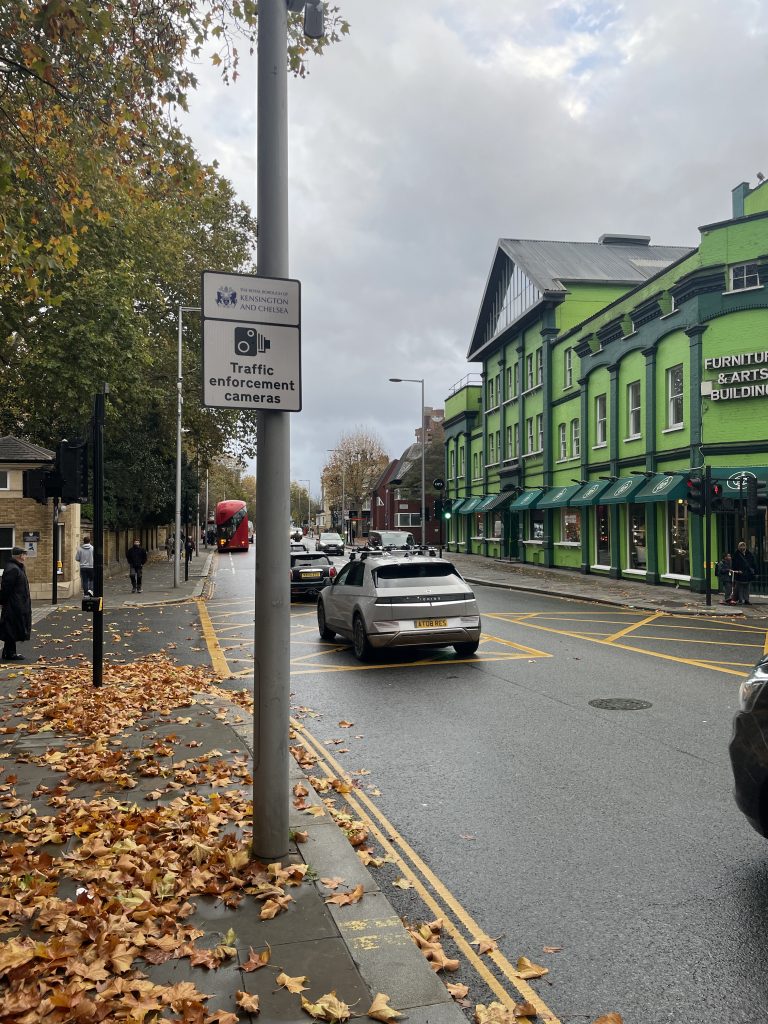 Traffic enforcement camera sign at a yellow box junction on a cloudy day.